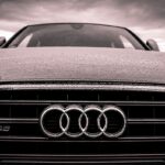 Αυτοκίνητο Audi στον δρόμο υπό βροχή με τον σήμερα της εταιρείας στον προφυλακτήρα