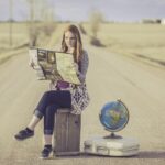 Νεαρή γυναίκα με τη βαλίτσα έτοιμη ψάχνει στον χάρτη τον επόμενο προορισμό της