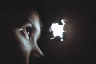 Μικρό παιδί κοιτάζει μέσα από τρύπα σε χαρτόνι