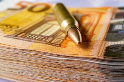 Ένα βλήμα πάνω σε χαρτονομίσματα ευρώ, συμβολίζοντας το κόστος εξοπλισμών στον πόλεμο