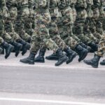 Στρατιώτες με στολή παραλλαγής βαδίζουν σε σχηματισμό σε στρατιωτική παρέλαση