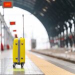Κίτρινη βαλίτσα σε σιδηροδρομικό σταθμό