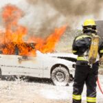Πυροσβέστης προσπαθεί να σβήσει τη φωτιά από φλεγόμενο αυτοκίνητο