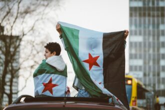 Αγόρι τυλιγμένο με τη σημαία της Συρίας πάνω σε αυτοκίνητο