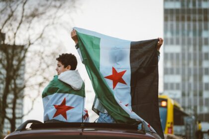 Αγόρι τυλιγμένο με τη σημαία της Συρίας πάνω σε αυτοκίνητο