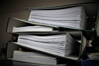 Stacks of documents on a desk in a German office illustrating bureaucracy burden