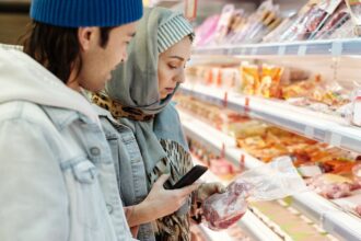 Woman checking food prices in a German supermarket aisle