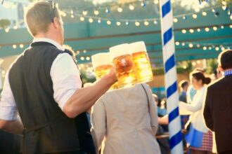 Visitors raising steins inside a decorated Oktoberfest beer tent in Munich