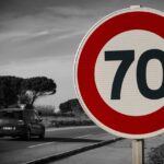 Speed limit sign on German countryside road with cars passing