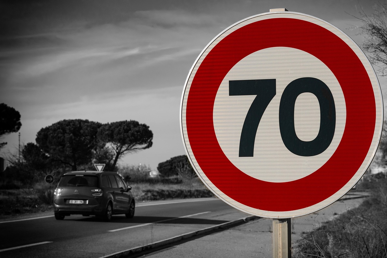 Speed limit sign on German countryside road with cars passing