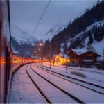Night train arriving in a snowy Alpine town during winter