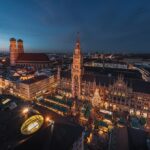 Evening view of Munich’s Marienplatz Christmas market with festive lights and wooden stalls.