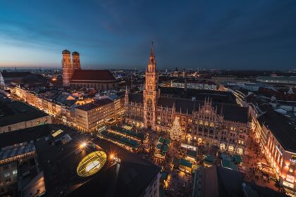Evening view of Munich’s Marienplatz Christmas market with festive lights and wooden stalls.