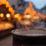 Steaming mug of Glühwein at Nuremberg’s Christkindlesmarkt with festive lights behind